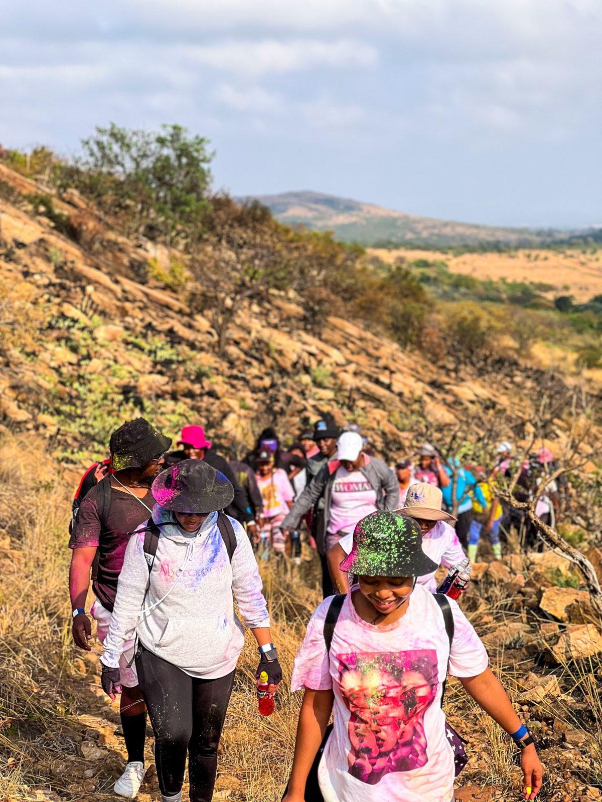Hikers covered in colour powder walking a rocky hillside